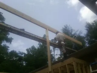 Carpenter setting a ridge beam over a new addition frame — Ice Dam Removal by Roofing Brothers in Lowgap