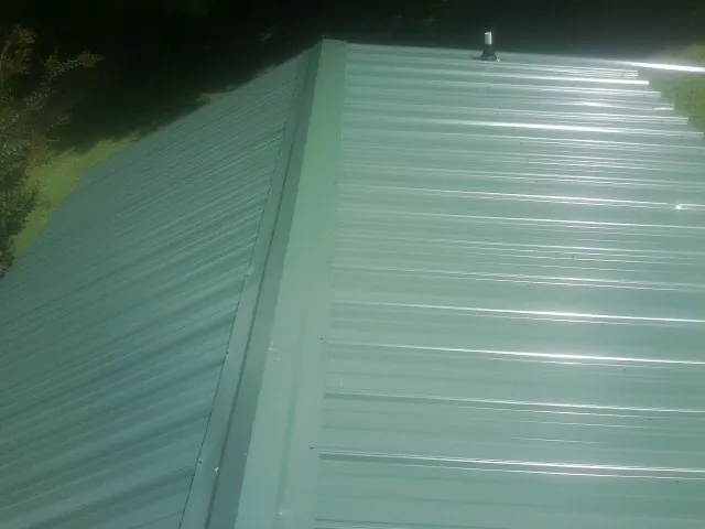 New green metal panels meeting at the ridge of a roof — Flat Roof Repair work by our crew in Lowgap