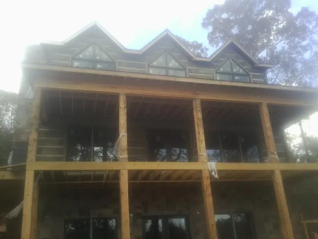 Dormers and porch framing on a large log home under construction — Roof Coating work by our crew in Lowgap