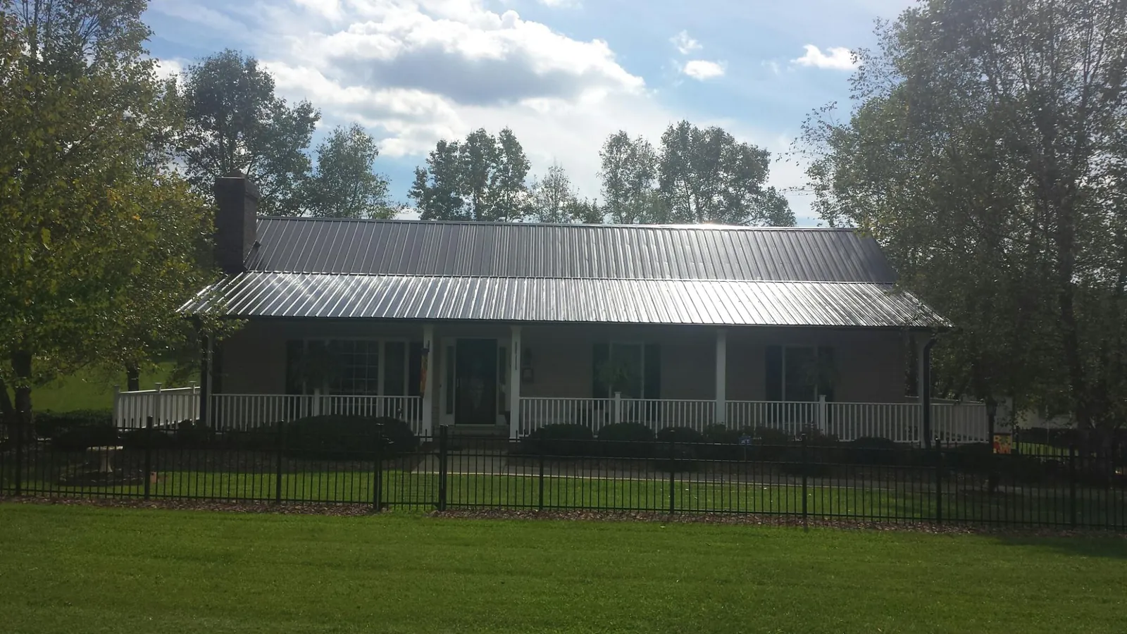 Gray metal roof on a brick ranch with a full width front porch — Gutter Guard Installation work by our crew in Lowgap