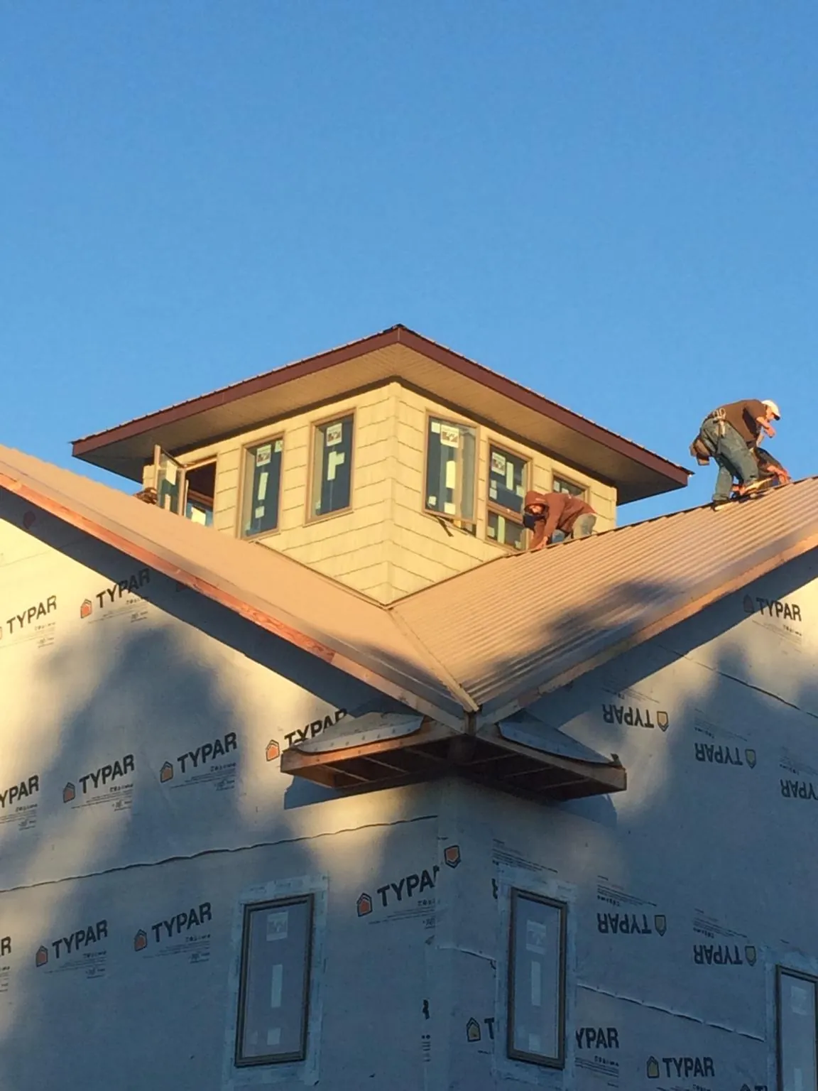 Roofers working around a rooftop cupola on a new metal roof at sunset — Roof Waterproofing in Lowgap by Roofing Brothers